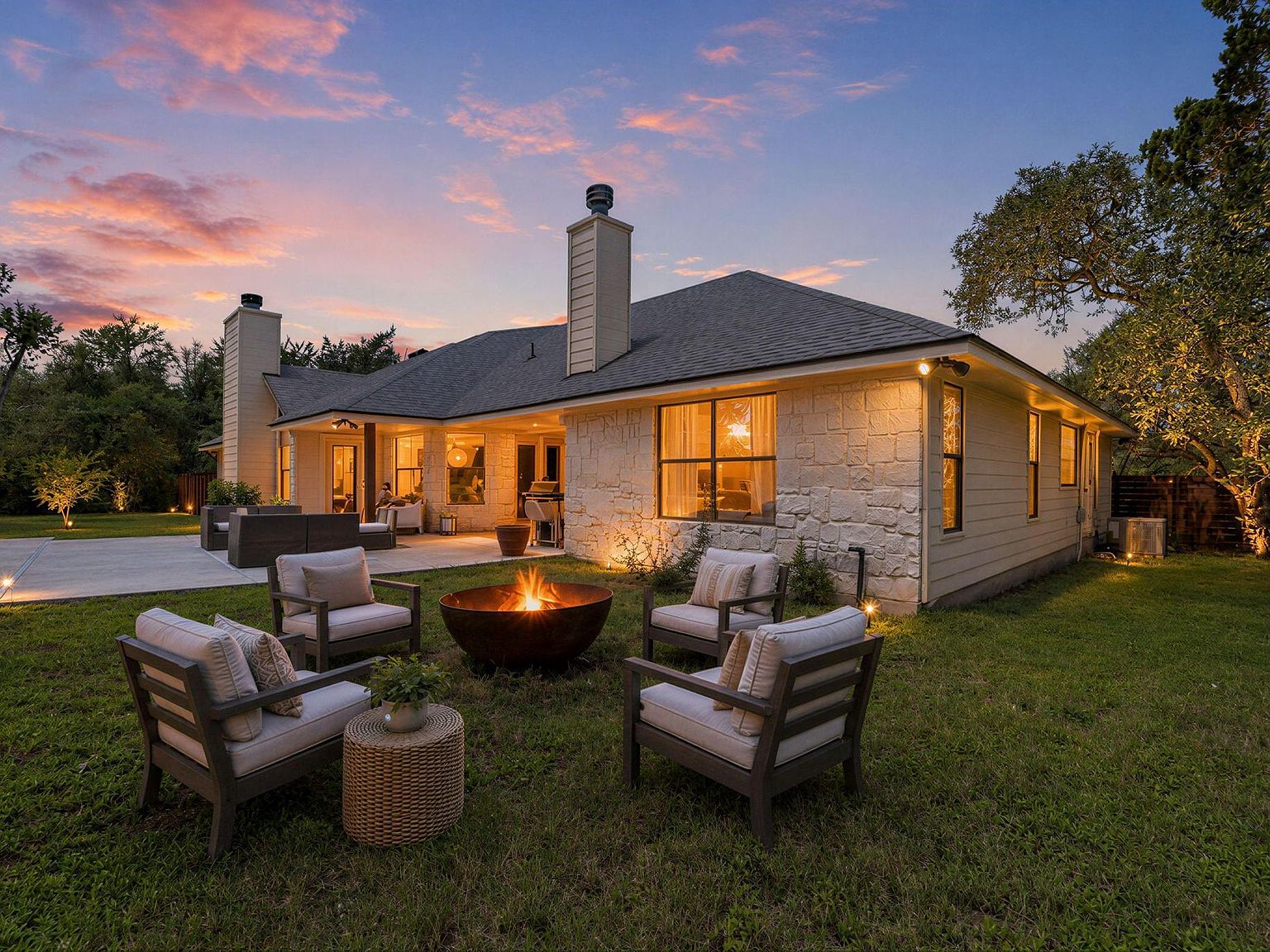 Rear elevation opening to a covered patio with the level three-quarter-acre lot stretching to the perimeter trees