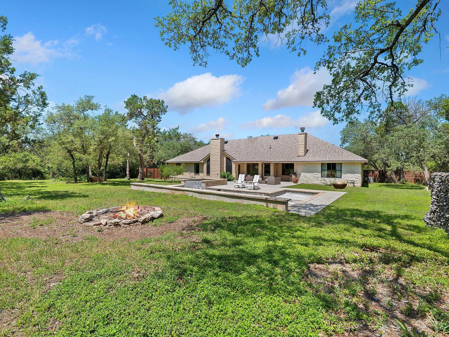 Single-story Spanish Ranch facade at 105 N Laurelwood Drive seen from the front lawn under West Austin live oaks